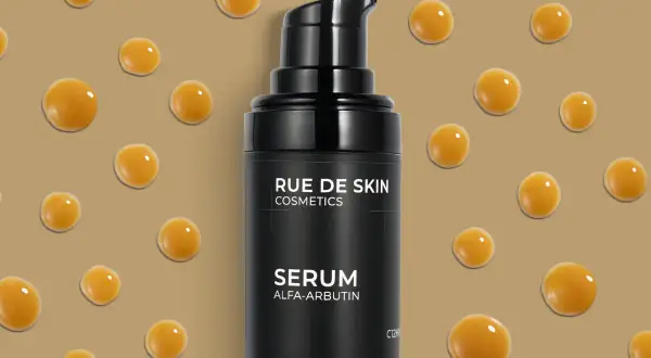 Czarny flakonik serum z alfa-arbutyną, otoczony kropelkami o bursztynowym odcieniu. Idealny do nocnej pielęgnacji.