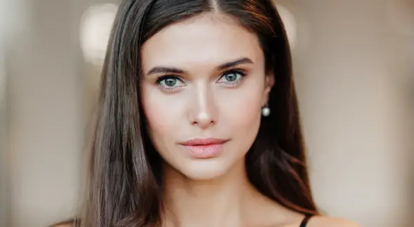 Portret młodej kobiety z naturalnym makijażem oczu i ust.