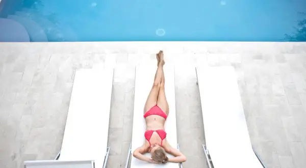 Kobieta w bikini odpoczywa przy basenie. Cieszy się słońcem po zabiegu depilacja bikini płytkie.